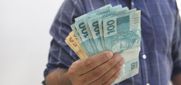 Businessman's hand with Brazilian real notes, creating a loan