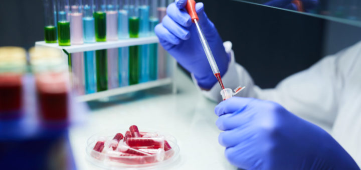 Close up of unrecognizable scientist dropping blood samples in test tubes while working on research in laboratory, copy space